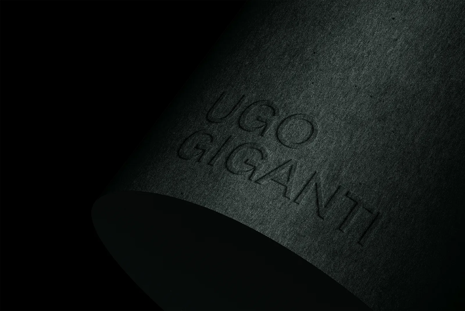 Nom Ugo Giganti embossé sur un papier sombre