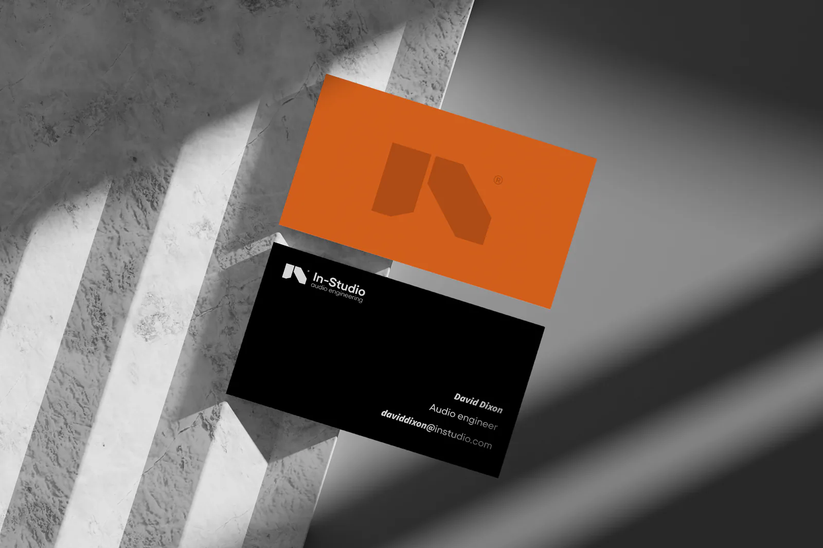 Cartes de visite In-Studio orange et noire posées sur du marbre