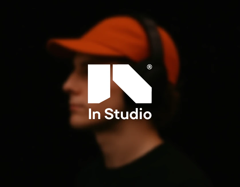Logo In Studio blanc sur le portrait flou d'un homme en casquette orange et casque audio
