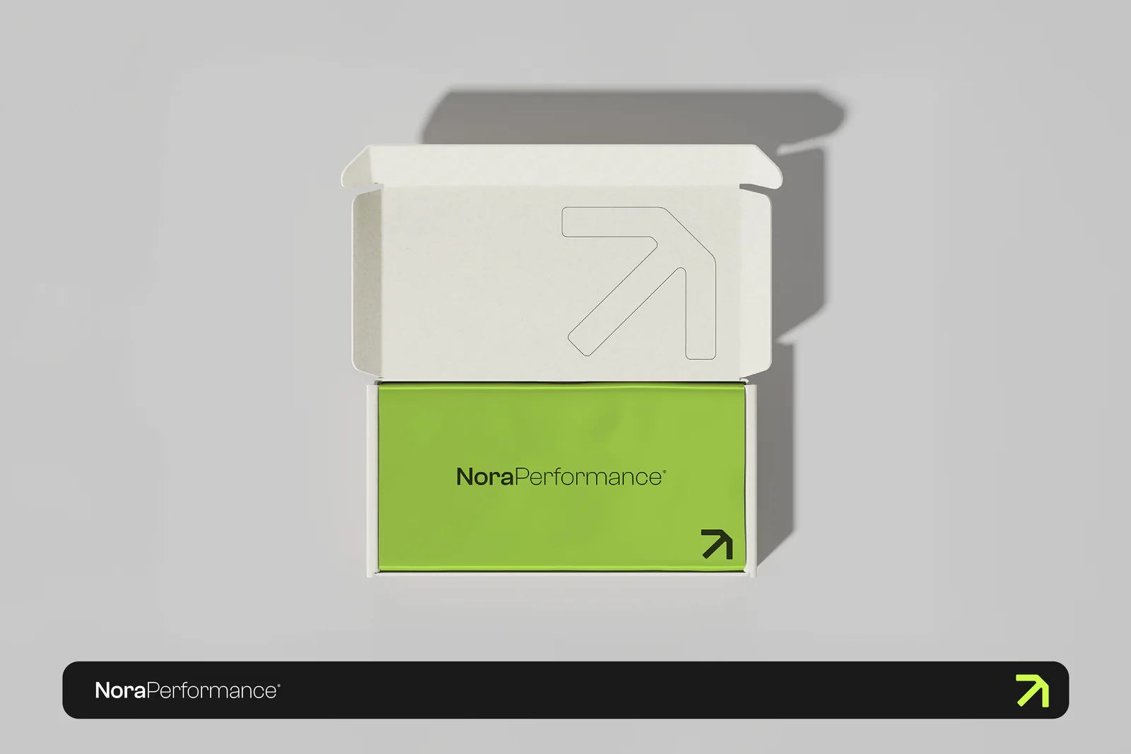 Coffret d'expédition Nora Performance ouvert, avec la flèche en ligne et le sachet vert